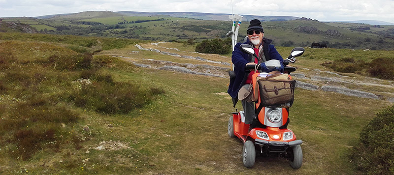 Person using mobility scooter on moorland with tramway and views in background